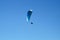 Paraglider soaring in the clear blue sky.