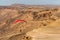 A paraglider soars over the Israeli desert