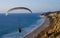 A paraglider takes in vast ocean view while gliding along beach and cliffs