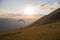 A paraglider taking off from Monte Cucco Umbria, Italy,at almost sunset, with people watching