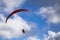 Paraglider with two people tandem flying against blue sky with clouds