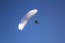 A paraglider on a white parachute in the blue sky