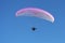 Paraglider white-pink colors against the blue sky