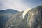 Paraglider with a wing gliding in the air in front of a mountain in bohinj, slovenia, in julian alps during a sunny afternoon.