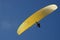 Paraglider with yellow chute against deep blue sky