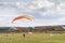 Paragliders flying under blue sky in a green field