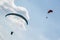 Paragliders seen from below in partially clouded sky