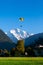 Paragliding flying over green field Hohematte park and Swiss alps in Interlaken, Switzerland