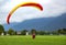 Paragliding instructor with a tourist under a raised yellow-red wing