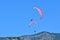 Paragliding. Two paragliders on a blue sky and mountains background.