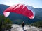 Paragliding. Woman with a red paraglider on the top of the mountain.