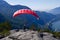 Paragliding. Woman with a red paraglider on the top of the mountain.