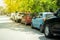 Parallel cars parking on street with green trees