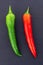 Parallel vertical green red chili pepper on a black background long pods close-up