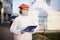 Paramedic wearing face shield and personal protective equipment holding patient clipboard form standing next to triage tent