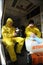 Paramedics sitting in the ambulance car putting yellow protective costumes and masks on to disinfect coronavirus