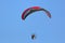 Paramotor pilot flying in a blue sky