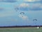 Paramotor pilot flying over a field of white flowers. The white car with balloons tied to chairs and tripods are props includes a