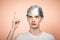 Paranoid young man wearing tin foil hat pointing up studio shot on salmon background