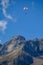 Paraplaners in tandem gliding in blue sky and Alpine mountains on paraplane