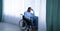 Paraplegic black man in wheelchair feeling depressed and lonely, looking out window at home, panorama