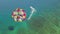Parasailing in blue sea drone view. Aerial view parasailing in sea bay. Colorful parasail wing pulled by sailing boat in