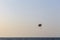 Parasailing in Dubai - single colorful parasail parachute tendem wing flying, towed behind a boat before sunset