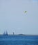 Parasailing in ocean with sailboat, lighthouse and shoreline