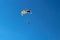 Parasailing water amusement. Beautiful bright blue sky and colorful parachute on which flies an adult man