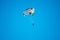 Parasailor on multi-colored parachute flying in blue clear sky, sunny weather, inspirational, summer, vacation