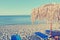 Parasols and sun loungers on white sandy beach; faded, retro style