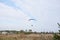 Paratrike with blue parachute flying high in the cloudy sky on autumn morning. Paragliding activity in rural countryside. Weekend