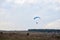 Paratrike with blue parachute flying high in the cloudy sky on autumn morning. Paragliding activity in rural countryside. Weekend