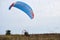 Paratrike with blue parachute ready to fly high in the cloudy sky. Paragliding activity in rural countryside. Weekend leisure time