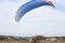 Paratrike with blue parachute ready to fly high in the cloudy sky. Paragliding activity in rural countryside. Weekend leisure time