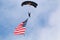 Paratrooper jumping with american flag attached to him.