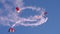 Paratroopers in red and white of the Swiss flag perform spirals in the blue sky