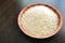 Parboiled rice on a bamboo bowl on wood table.