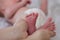 The parent gently holds the little feet of the newborn baby in his hands. Mom and Child. A beautiful conceptual image of