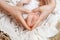 Parent holding in the hands feet of newborn baby.  Tiny newborn baby`s feet on heart hands closeup. Mom and her child. Happy