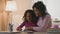 Parent proud. Caring african american mother helping her daughter with homework, kissing and embracing her clever kid