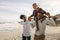 Parents carrying son on shoulders on beach vacation