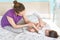 Parents and children concept. Attractive young woman plays with her son in bedroom, tickles him, have fun after awakening and good