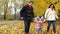 Parents with children playing in the park with yellow leaves in