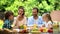 Parents and children sitting at table, enjoying family dinner, having fun, joy