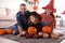 Parents and cute little girl with pumpkin having Halloween party at home