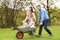 Parents Giving Children Ride In Wheelbarrow