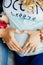 Parents hands making heart on belly of the pregnant mother