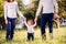 Parents holding hands of their son making first steps