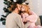 Parents hug and kiss their beloved daughter. Young family in a Christmas decorated room.